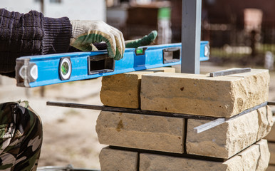 The worker is laying bricks on the fence