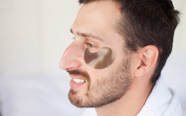 Fototapeta premium Bearded man is using anti-wrinkle mask