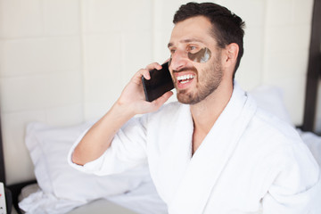 Man Eating Breakfast In Bed Whilst Using Mobile Phone