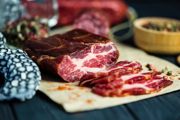 dried pork neck with spices on paper on wooden background