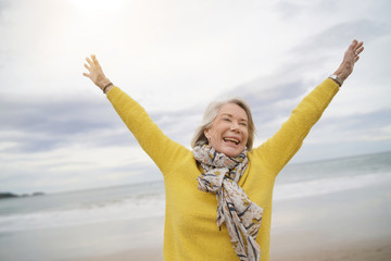  Carefree energetic senior woman playing around on beach in fall