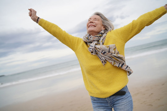  Carefree energetic senior woman playing around on beach in fall