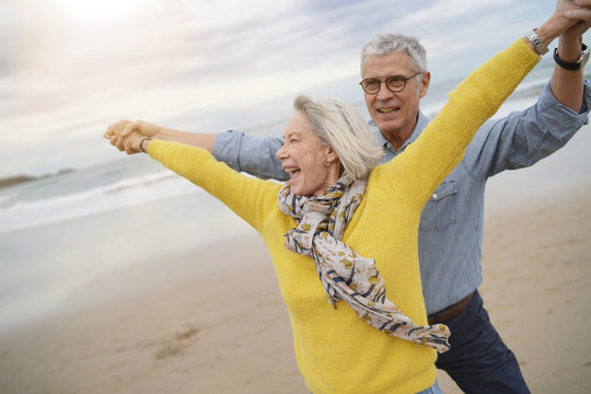  Lively Senior Couple Playing Around On Beach Together