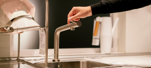 hand opens the kitchen water faucet tap close up f
