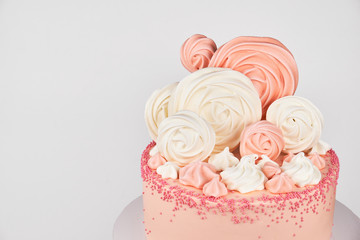 Birthday pink cake, decorated with meringue cookies on a white background.
