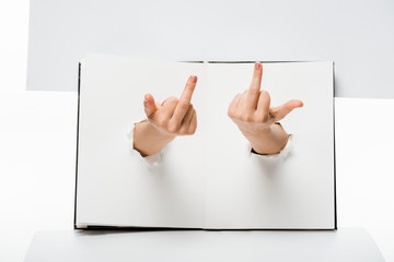 cropped shot of woman showing middle fingers through holes on white