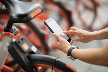 Hands using smartphone scanning the QR code of shared bike in city