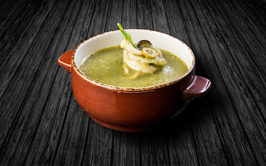 Soup of squid with spinach. On a wooden table. In a ceramic pot1