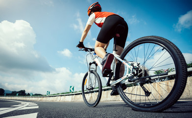 Obraz premium Woman cyclist riding Mountain Bike on highway