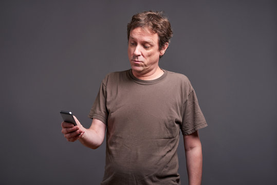A middle age man standing and using a smartphone
