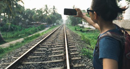 Woman tourist using mobile phone taking photo of rail way