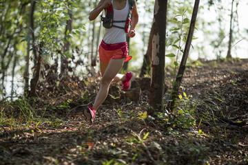 Sportswoman cross country trail running in forest