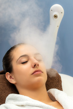 Woman having facial steam treatment in spa.