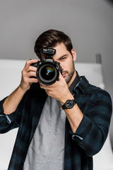 handsome young male photographer shooting with professional camera