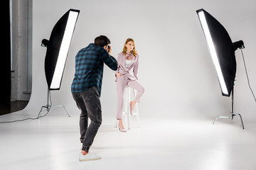 back view of photographer shooting beautiful young female model in photo studio - Powered by Adobe