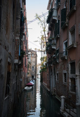 Fototapeta na wymiar Narrow dark streets of Venice. Brick walls and windows. Water.