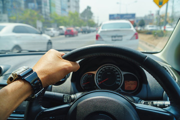 Driver's hands on the steering wheel inside of a car, While driving in the sunlight in front of the driver. Should drive with caution.