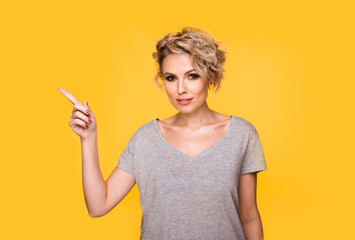 Happy surprised blonde young female smiling broadly at camera, pointing fingers away, showing...