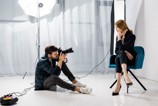 young male photographer shooting beautiful model in studio