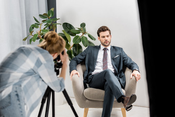 young female photographer shooting handsome businessman in studio