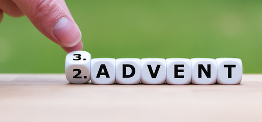 Hand is turning a dice and changes the word "2.Advent" to "3.Advent" as symbol for the upcoming third Advent