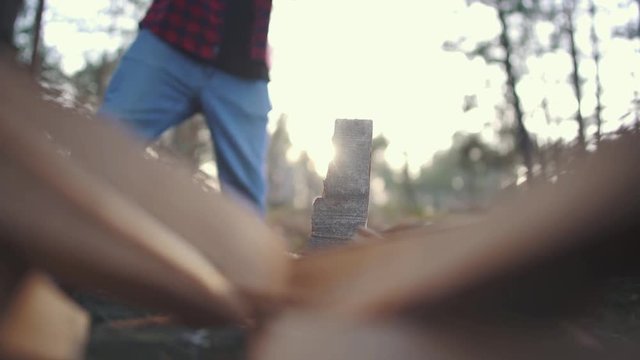 A guy chops wood with axe in forest. Slow motion.