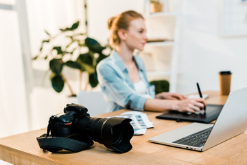 close-up view of photo camera and photographer using drawing tablet behind