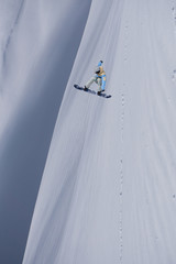 Snowboarder flying on the background of snowy slope. Extreme winter sports, snowboarding. Copy space.