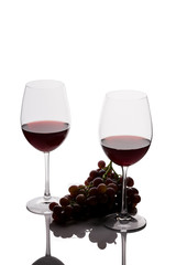 Two glasses of wine and grapes on white background
