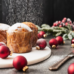 Sprinkling powdered sugar over traditional Christmas mini Panettone with raisins and dried fruits...