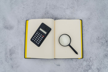 notepad, calculator, magnifier on the background of snow