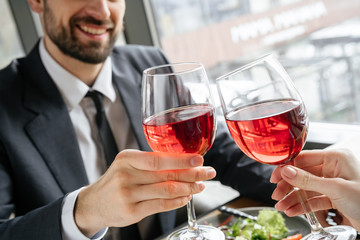 Businesspeople having business lunch at restaurant sitting eating salad drinking wine cheers glasses close-up