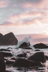 Surfer on the rocks with the board in his hand waiting to jump into the sea.
