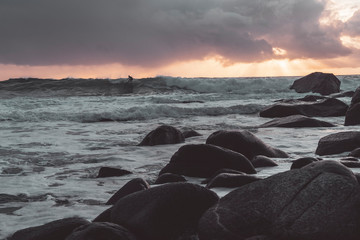 Surfer on the wave photographed from shore to sunset.