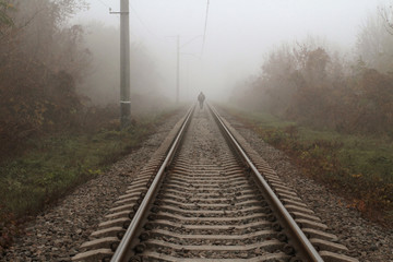 Fototapeta na wymiar Lonely man in the fog goes by rail