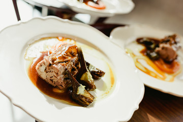 Many dishes loin of pork confit with artichokes and juicy sauce served by waiters in a luxury restaurant.