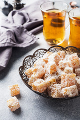 Turkish delight with hazelnut in carved metal bowl and tea in glass Cup, selective focus