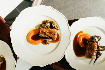 Many dishes loin of pork confit with artichokes and juicy sauce served by waiters in a luxury restaurant.