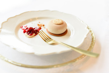 Ice cream dessert elegantly presented with strawberry jam in luxury dishes and golden linens.
