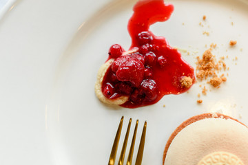 Ice cream dessert elegantly presented with strawberry jam in luxury dishes and golden linens.