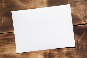 Blank white paper rests on a brown wooden floor with copy space for design in your work.