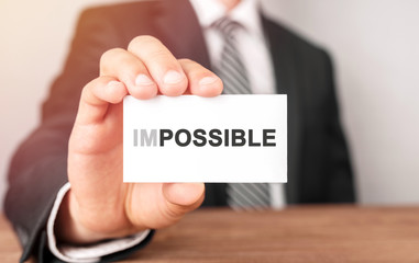 Businessman holding a card with text Impossible