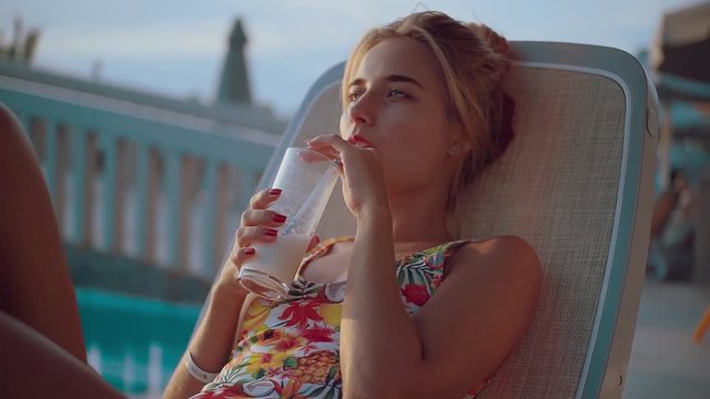 Attractive blonde girl drink cocktail and relaxing on an inflatable circle happy holiday pool summer vacation water woman young rest close up portrait slow motion