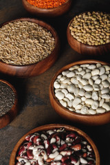 variety of beans with oat groats in wooden bowls on table