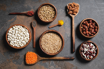 flat lay of wooden bowls and spoons with superfoods, legumes and grains on table