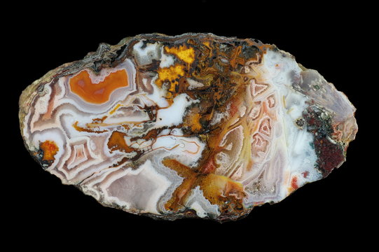 A cross-section of agate. Agates in agate - polycentric, with color. White chalcedony with quartz, jasper and pseudomorphs. Origin: Agouin, Atlas mountains, Morocco.