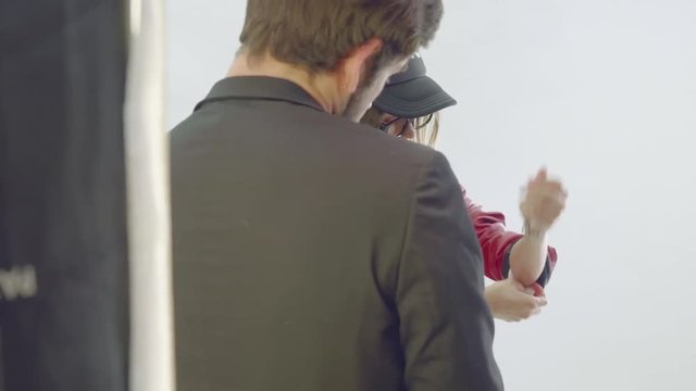 Man helps female model to adjust clothes during photoshoot