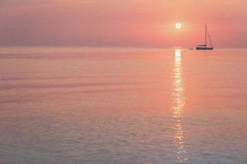 Rising sun and a sailing boat in coral sunrise