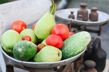 Old rusty scales weighting fruits and vegetables such as pears, tomatoes and cucumbers. country marketplace on warm autumn day, harvest festival