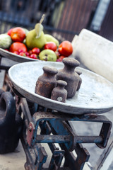 Old rusty scales weighting fruits and vegetables such as pears, tomatoes and cucumbers. country marketplace on warm autumn day, harvest festival